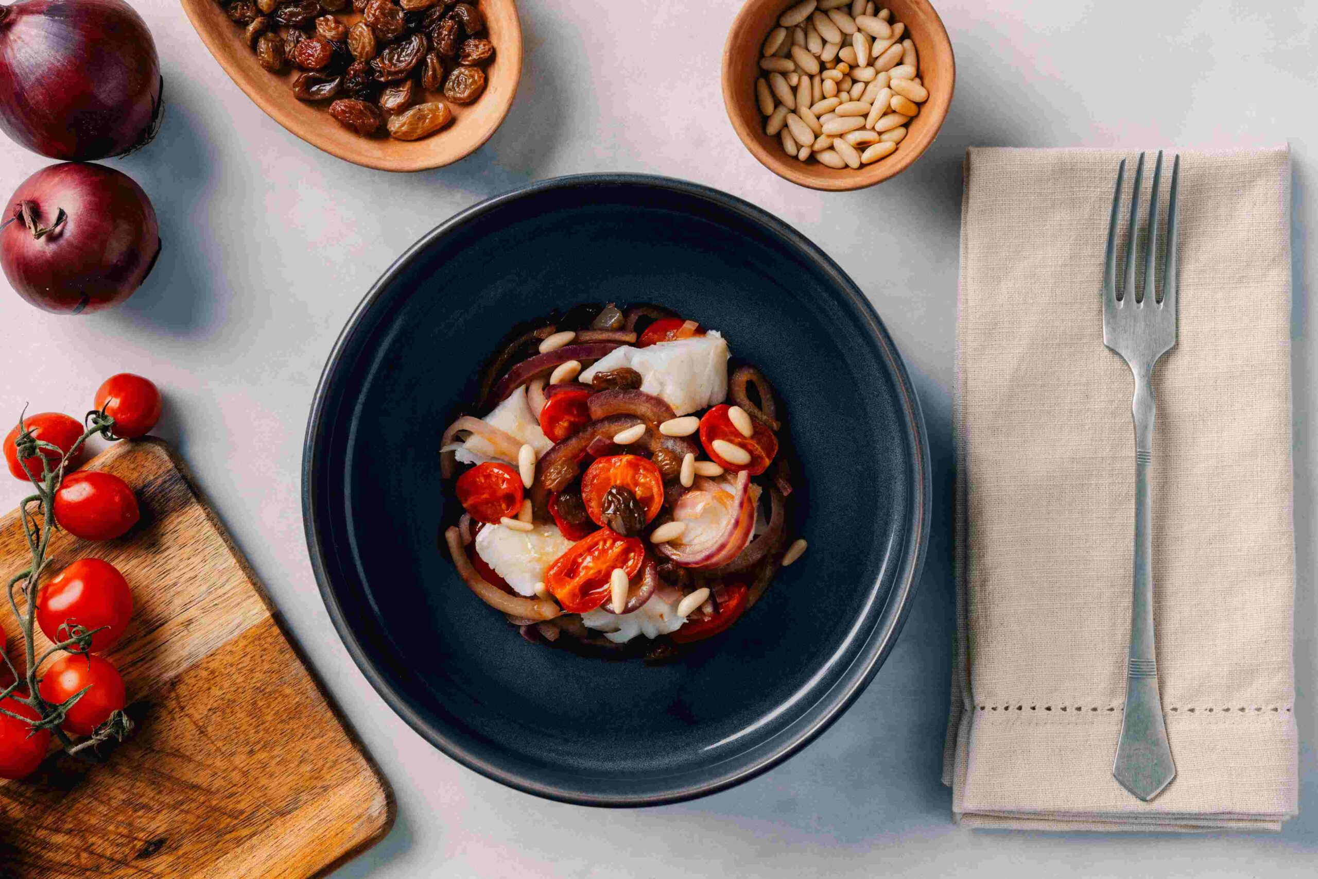Cod with cherry tomatoes, pine nuts and raisins