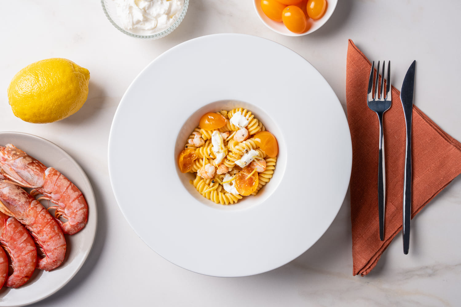 Fusilli pasta with yellow cherry tomato sauce, shrimp, and raw stracciatella cheese
